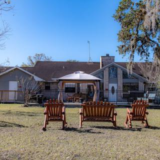 A tranquil view of a house with wooden chairs in the foreground, perfect for enjoying the outdoors.