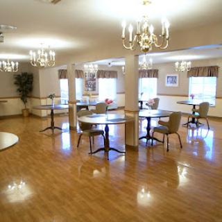 A bright and spacious dining area featuring tables and chairs under elegant chandeliers.