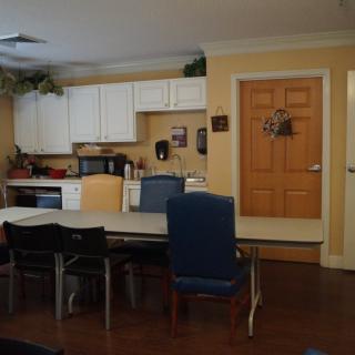 A cozy kitchen interior with a dining table and chairs, surrounded by cabinets and appliances.
