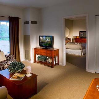 A cozy living room with a view into the bedroom, featuring a television and comfortable furnishings.