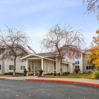 A building with a prominent entrance, surrounded by autumn trees and a circular driveway.