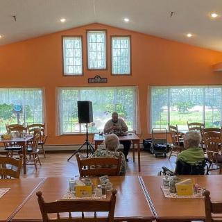 A small gathering in a dining area with orange walls and large windows.