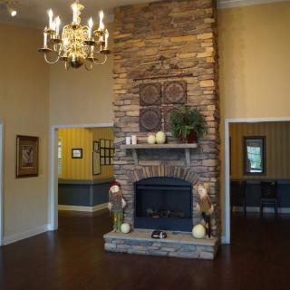 A cozy living room with a stone fireplace and elegant chandelier.