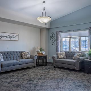 A cozy living room with two gray sofas and a decorative chandelier.