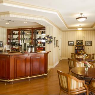 A cozy cafe interior featuring wooden furniture and a small bar area.