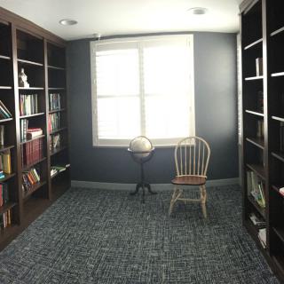 A cozy library with bookshelves and a chair by the window.