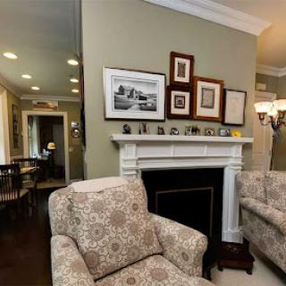 A cozy and elegantly designed living room featuring a fireplace, comfortable armchairs, and curated wall art.