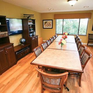 A well-lit conference room with a long table and chairs, featuring a television and bookshelves.