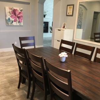 A modern dining room with a dark wooden table and chairs, adorned with a small flower arrangement.