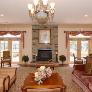 A cozy living room with a central fireplace, elegant chandelier, and comfortable seating.