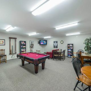 A game room featuring a red pool table, seating area, and wall-mounted television.