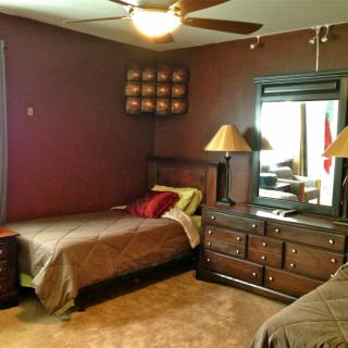 A cozy bedroom with twin beds, a dresser with mirror, and warm lighting.