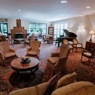 A spacious living room featuring comfortable seating, a grand piano, and a cozy fireplace.