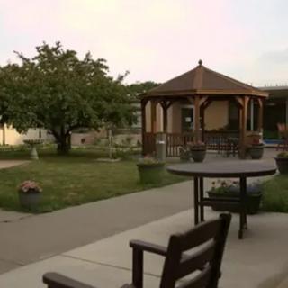 A peaceful garden with a wooden gazebo and outdoor seating.