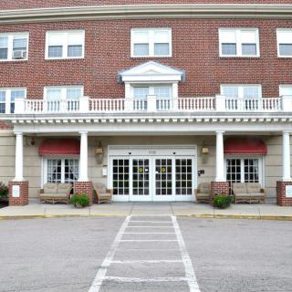 A brick facade hotel entrance with white columns and large glass doors.