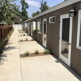 A row of modern tiny homes with a concrete pathway and minimal landscaping.