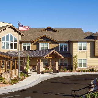 A two-story modern residential building with a welcoming entrance and well-kept landscaping on a sunny day.