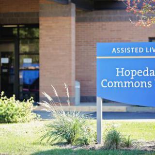 Entrance of Hopedale Commons Assisted Living facility with a sign in front.