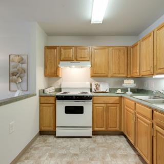 A clean and organized kitchen with wooden cabinets and a white stove.