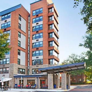 A modern apartment building set in an urban environment with surrounding trees and outdoor amenities.