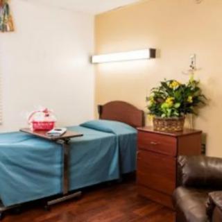 A hospital room with a bed, bedside table, and a basket of flowers.