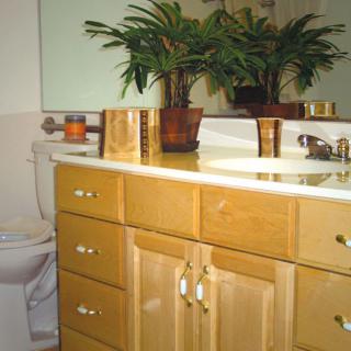 A well-organized bathroom featuring a wooden cabinet, sink, mirror, and indoor plants.