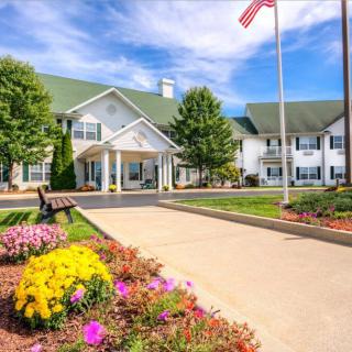 A picturesque garden path leading to a large white building, adorned with colorful flowers and an American flag.