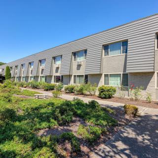 A modern building exterior with neatly landscaped surroundings under a clear blue sky.