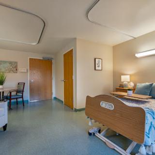 A well-designed patient room in a healthcare facility, featuring a hospital bed and cozy furniture.
