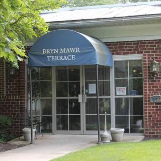 Entrance to a building with a blue awning labeled 'Bryn Mawr Terrace'.
