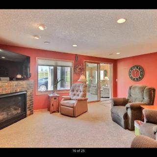 A cozy living room featuring a fireplace, armchairs, and large windows.
