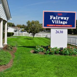 A welcoming sign for Fairway Village, surrounded by well-maintained greenery.
