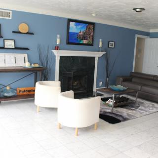 A modern living room with blue walls and contemporary furniture, featuring a fireplace and a mounted television.