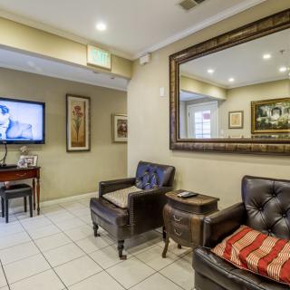 A comfortable waiting room featuring leather chairs, a large mirror, and a wall-mounted television.