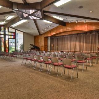 An empty auditorium with arranged seating and a stage featuring a grand piano.