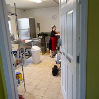 A glimpse into a busy kitchen where a woman is preparing food.