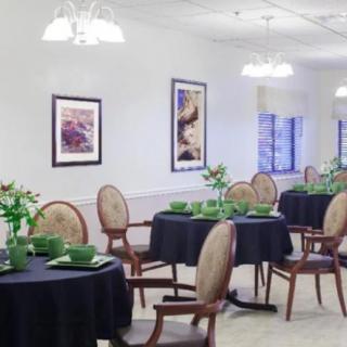 A well-decorated dining room with tables set for a meal, featuring elegant chairs and framed artwork on the walls.