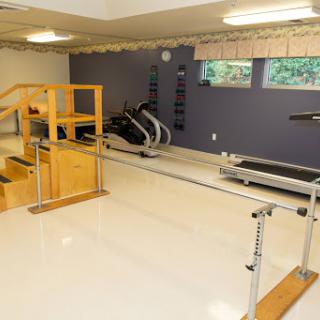 A well-equipped home gym featuring exercise machines and a wooden railing for support.