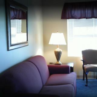 Cozy living room with a sofa, lamp, and chair near a window.