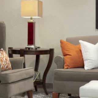 A cozy living room setup featuring a sofa and armchair with colorful pillows, a side table, and a lamp.