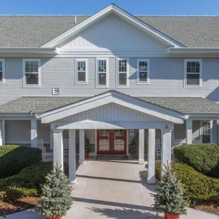 A front view of a residential building with a covered entrance and landscaped surroundings.