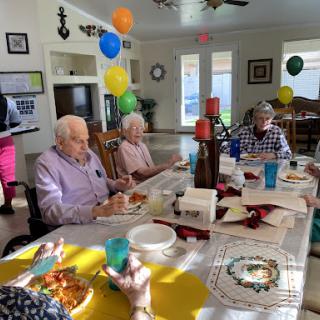 A cheerful birthday party with seniors enjoying food and decorations, surrounded by balloons and lively conversations.