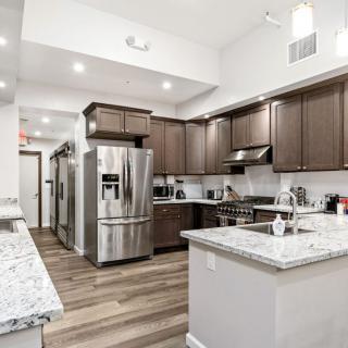 A spacious modern kitchen with stainless steel appliances, wooden flooring, and granite countertops.