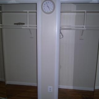 An empty closet with a wall clock mounted above the center divider.