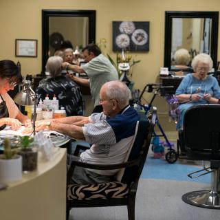 Senior citizens enjoying a day of self-care at a beauty salon, with activities like hairdressing and nail care.