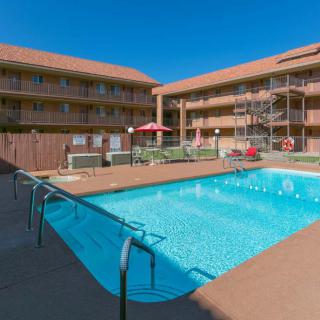 An outdoor swimming pool at an apartment complex under a clear blue sky.