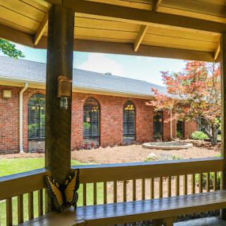 A peaceful view from the porch, showcasing a beautifully landscaped brick home.