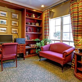 A cozy office space with a desk, computer, bookshelves, and a small sofa near a window.