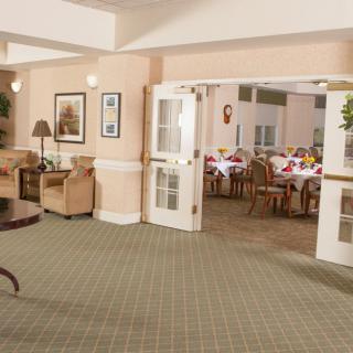 A cozy lounge area leading into a dining room, featuring comfortable chairs and tables.