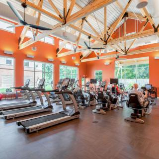 A spacious gym with various exercise machines, including treadmills and stationary bikes, in a well-lit environment.